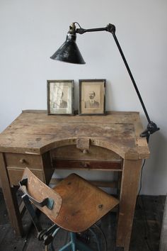 an old wooden desk with two pictures on it and a chair in front of it