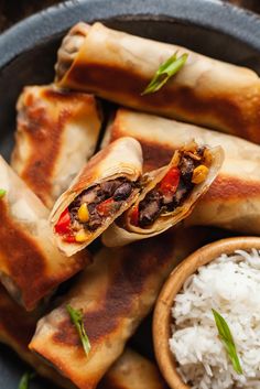 a plate with rice, meat and vegetable spring rolls