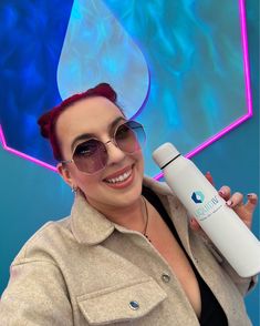 a woman in sunglasses holding up a water bottle