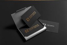 two black business cards sitting on top of each other next to an envelope with gold foil