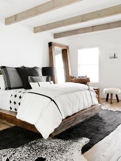 a white bed with black and white comforter in a bedroom next to a window