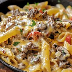 a skillet filled with pasta and meat covered in cheese, sauce and parsley