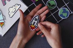 a person is holding a small pixel art piece in their hand and it's surrounded by stickers