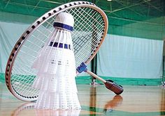 a badminton racquet and shuttle on a wooden floor in an indoor court area