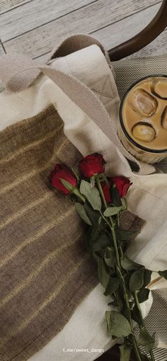 a red rose sitting on top of a table next to a cup of coffee and a blanket