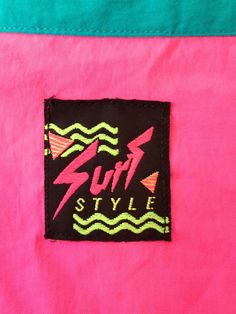 a patch on the side of a pink and blue jacket that says surf style with waves