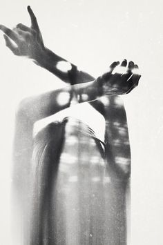 a black and white photo of a woman's hands reaching out to the sky