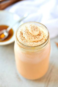 a glass jar filled with liquid sitting on top of a table next to a spoon