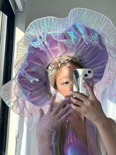 a woman taking a selfie with her cell phone wearing a purple dress and hat