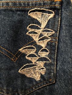 the back pocket of a pair of jeans with embroidered mushrooms on it