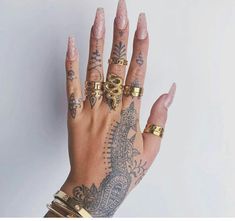 a woman's hand with tattoos and gold rings on her left wrist, holding onto the palm of her right hand