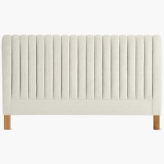 an upholstered headboard with wooden legs and pleated fabric, on a white background