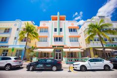 cars parked in front of multi - story building with palm trees and blue sky background