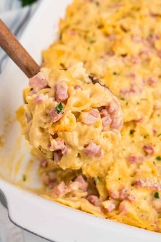 a casserole dish with ham and cheese in it being scooped from the casserole