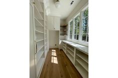 an empty room with lots of white shelves and windows in the wall, along with wood flooring