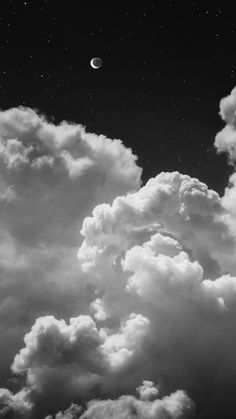 black and white photograph of clouds with the moon in the sky above them, as seen from below