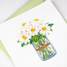 a card with daisies in a mason jar and twine tied around the stems