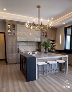 a large kitchen with an island in the middle and three stools at the end