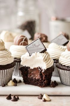 several cupcakes with white frosting and chocolate chips on a table next to other desserts