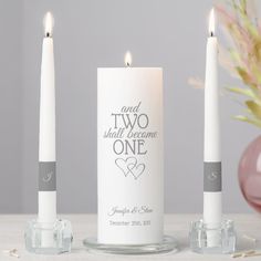 two white candles sitting next to each other on a table