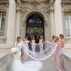 a group of women standing next to each other in front of a building with a veil over their heads