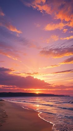 the sun is setting over the ocean with clouds in the sky and sand on the beach