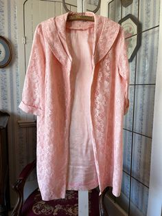 This lovely long jacket is made from gorgeous pink floral lace over a lightweight layer of matching pink satiny fabric. It has a wide collar and an open front with no buttons or snaps. The measurements, taken with the coat lying flat, are: shoulder to shoulder, 14 inches; armpit to armpit, 22 inches; sleeves, 17 inches; length, 37 inches; bottom edge, 26 inches. In very good condition. Elegant Pink Daywear Outerwear, Summer Wedding Long Sleeve Outerwear, Elegant Long Pink Robe, Vintage Pink Robe For Spring, Pink Long Sleeve Wedding Robe, Feminine Spring Wedding Robe, Feminine Spring Wedding Outerwear, Pink Feminine Robe For Spring, Spring Wedding Robe With Lace Trim