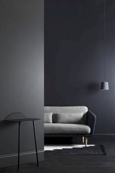 a black and white living room with a grey couch, table and lamp hanging from the ceiling