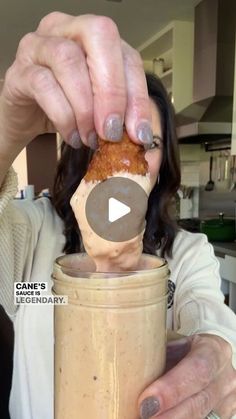 a woman holding a jar filled with food