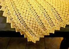 a yellow crocheted blanket sitting on top of a chair