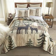 a bed covered in a comforter with moose and pine trees printed on the sheets