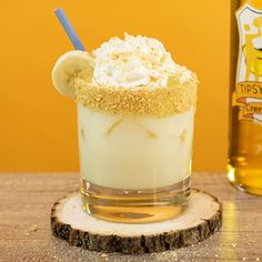 a banana milkshake with whipped cream on top and a bottle of beer in the background