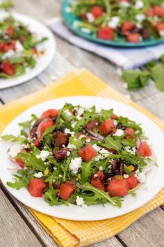 a salad with watermelon, feta cheese and tomatoes is on a white plate