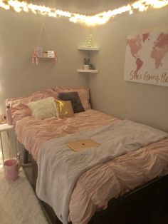 a bed with pink sheets and pillows in a room decorated with lights on the wall