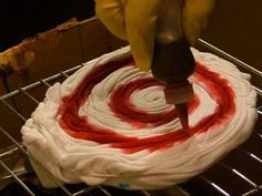 someone is decorating a cake with red and white icing