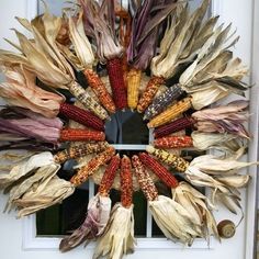 a wreath made out of dried corn on the cob is displayed in front of a door