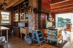 an old fashioned kitchen with wood flooring and brick oven in the middle of it