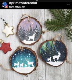 three christmas ornaments are hanging on a wooden table with pine branches and evergreens in the background