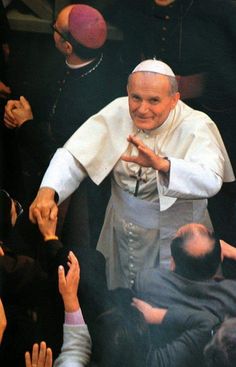 the pope is surrounded by people as he greets them with his hands in front of him