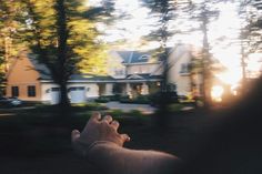 a person holding their hand out to the sun in front of a large white house