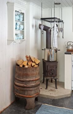 an old fashioned stove in a kitchen next to a barrel with wood stacked on it