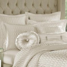 a bed with white comforters and pillows in a hotel room or home setting,