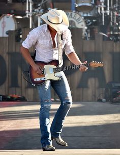 a man with a cowboy hat playing an electric guitar