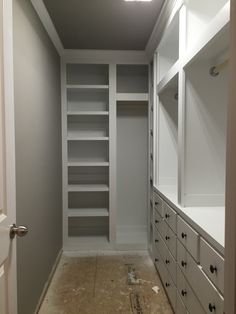 an empty walk in closet with lots of shelves and drawers on the wall, along with no doors