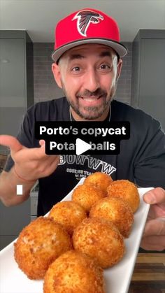 a man holding a plate full of potato balls and pointing to the camera with his finger