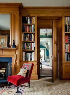 a red chair sitting in front of a book shelf filled with books