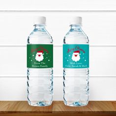 two water bottles with santa's hat and snowflakes on them, sitting on a wooden table