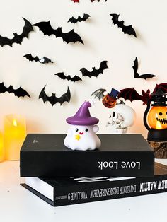 halloween decorations on top of a book with bats in the background and candles lit up behind them