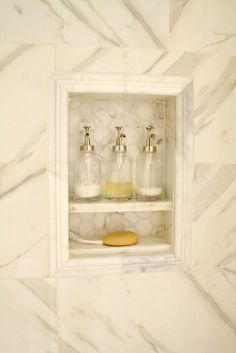 a marble bathroom with soap dispensers and toothbrushes on the shelf