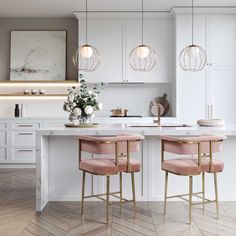 two pink chairs sitting at the end of a kitchen island